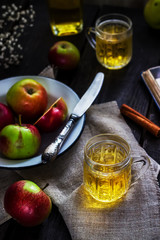 Cider and apples on white plate. Dark wooden table.