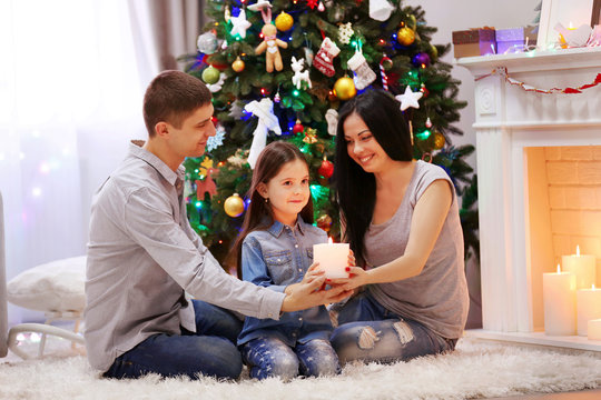 Happy family together hold candle in hands in the decorated Christmas room