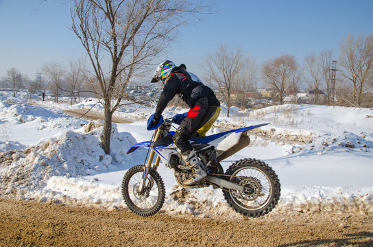 MX rider on a motorcycle flying against the backdrop of snowy hills