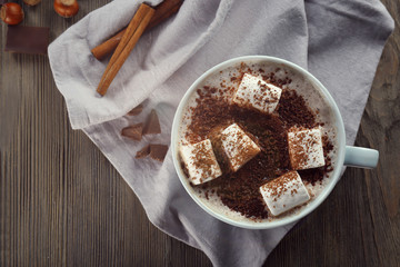 Cup of hot cacao with marshmallow, cinnamon and nuts on blue cotton serviette, close up