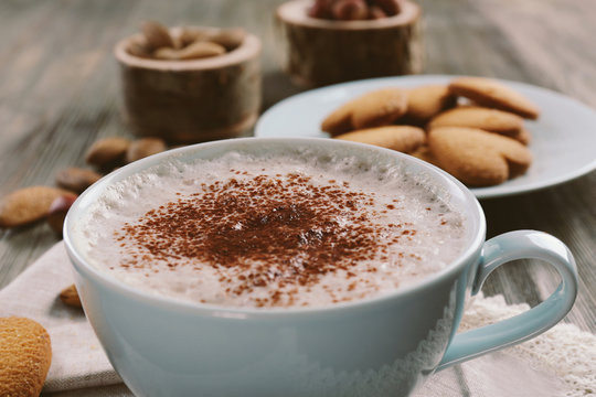 Cup of hot cacao on cotton serviette with cinnamon, almonds and heart shaped cookies, close up