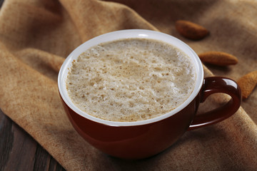Cup of hot cacao with almonds on cotton serviette, close up