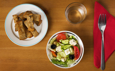 Salad with toasted bread along with water and fork
