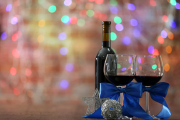 Red wine and Christmas ornaments on wooden table on Christmas lights background