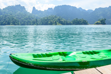 Green canoe in a beautiful mountains lake forest and river natural attractions in Ratchaprapha Dam at Khao Sok National Park, Surat Thani Province, Thailand.
