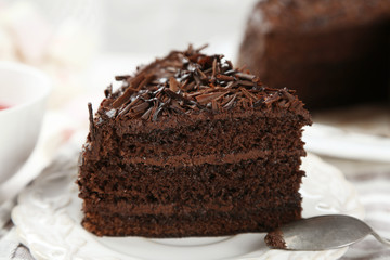 Sliced chocolate cake on wooden table, on light background