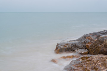Motion blur of stones on the sea beach under Cloudy sky with long exposure effect.