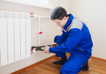 A plumber performs the installation of radiator heating