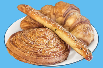 Croissant Puff Pastry Sprinkled with Sesame Seeds on Porcelain Plate, Isolated on Blue Background.