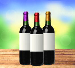 bottles of red wine on wooden table over bright nature backgroun