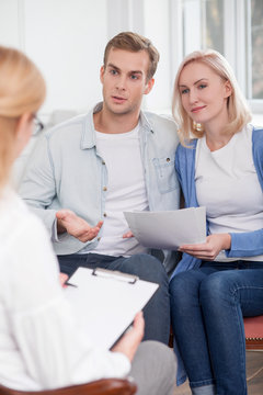 Cheerful husband and wife are asking advice in therapist