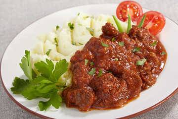 Goulash with mashed potatoes and tomato