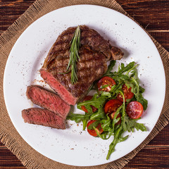 Ribeye steak with arugula and tomatoes.