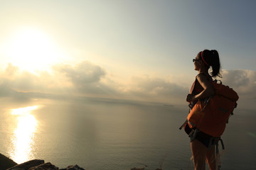 Fototapeta premium young woman backpacker at sunrise seaside mountain peak