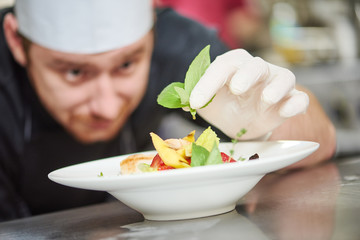 male cook decorating dish