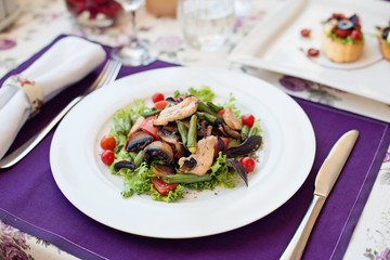 Salad with chicken and tomatoes in white plate on the table