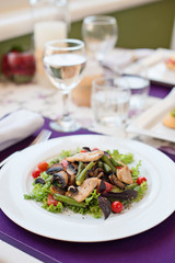 Salad with chicken and tomatoes in white plate on the table