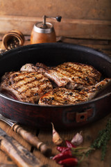 Grilled pork chop with spices in a frying pan