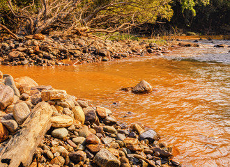 Small river with big stones on the coast and a red clay bottom in the tropical jungle of India