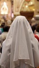 nun with white veil in prayer inside of the Christian Church