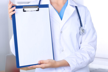 Smiling female doctor with a folder in uniform standing at hospital