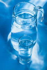 Glass of water with a jug on  blue background