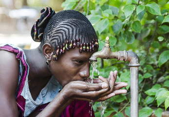 Happy African Schoolgirl Enjoying Clean Water from a Tap in Bamako, Mali