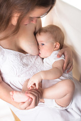 Mom feeds the baby breast, light background