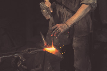 Blacksmith working metal with hammer