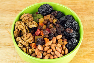 Mix nuts and dry fruits in plate on wooden background