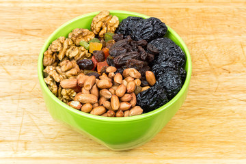 Mix nuts and dry fruits in plate on wooden background