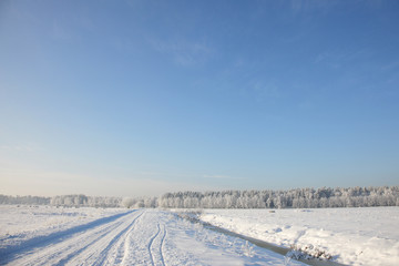 Fototapeta na wymiar Snow-bound field along the country road on a clear day