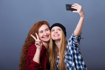 Two young smiling women taking selfie with mobile phone