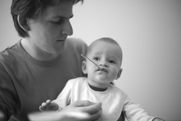 Father holding his mischievous baby with a spoon in mouth