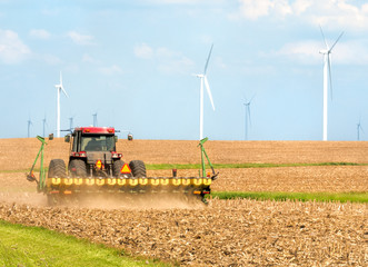 Farmer seeding soybeans in tractor in field near wind farm in Danville Illinois Midwest USA