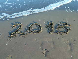 inscription year 2015 in the sand of the sea with waves