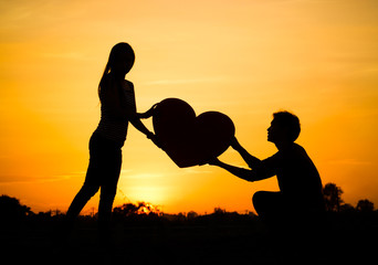 Man begging a woman for love by giving a big heart
