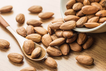 Almond in white bowl, spoon on the wood table