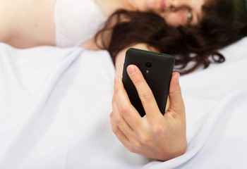 Beautiful young woman in white lingerie lying in bed and looking