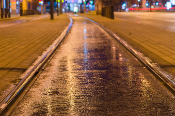 Tram rail track wet and shiny by night lights