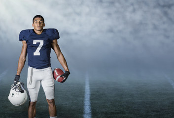 American Football player standing in a stadium at night ready to play and win