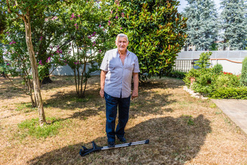 old man standing on crutches in garden