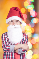 Portrait of a little Santa Claus with defocused bokeh Christmas lights background