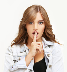Naklejka premium Young woman shushing,Girl holding finger on her lips.