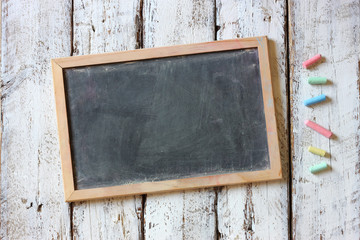 top image of chalkboard and colorful chalks over wooden table
