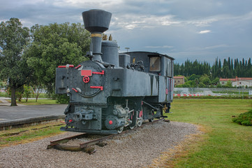 Naklejka premium Old steam locomotive at train station on cloudy day