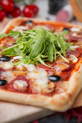 Homemade rectangular pizza on a rustic table with ingredients