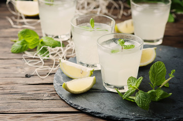 Obraz na płótnie Canvas Fresh cocktail with lemon, ice and mint on the vintage table