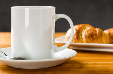 Kaffeebecher mit Croissants vor dunklem Hintergrund