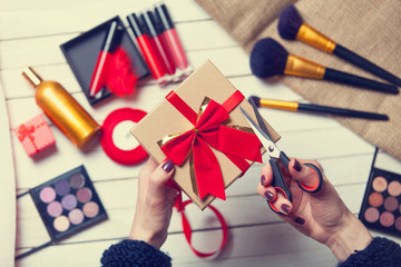 hands are wrapping cosmetics in christmas gifts